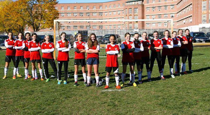 Girls youth soccer team standing in formation and crossing their arms