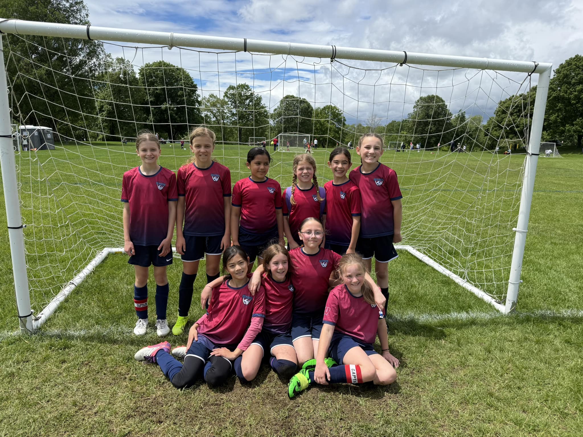 Girls soccer team standing and posing together in front of goal
